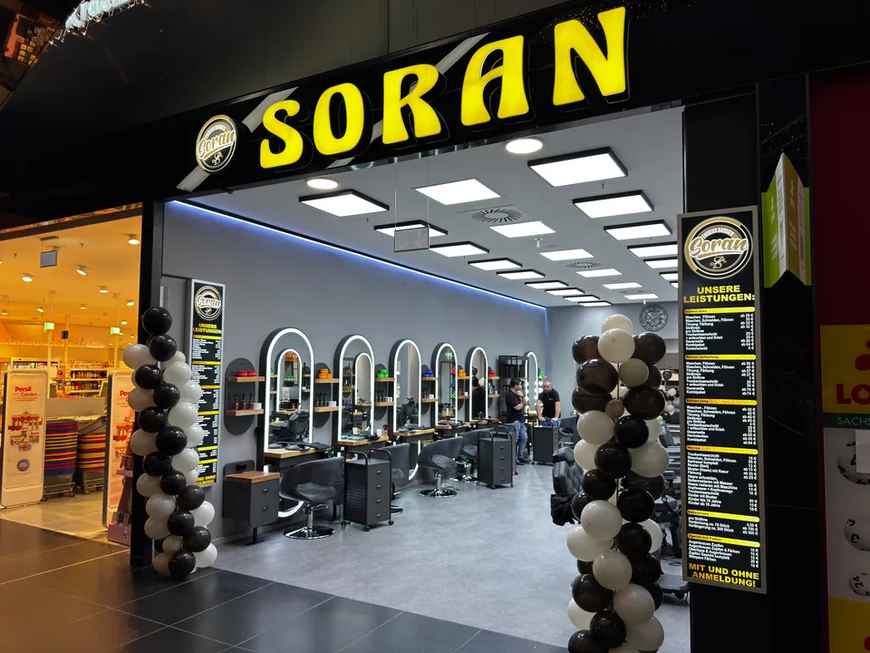 Eingang von Friseur Barbier Soran in den Höfen am Brühl in Leipzig mit dem Logo an der Fassade.