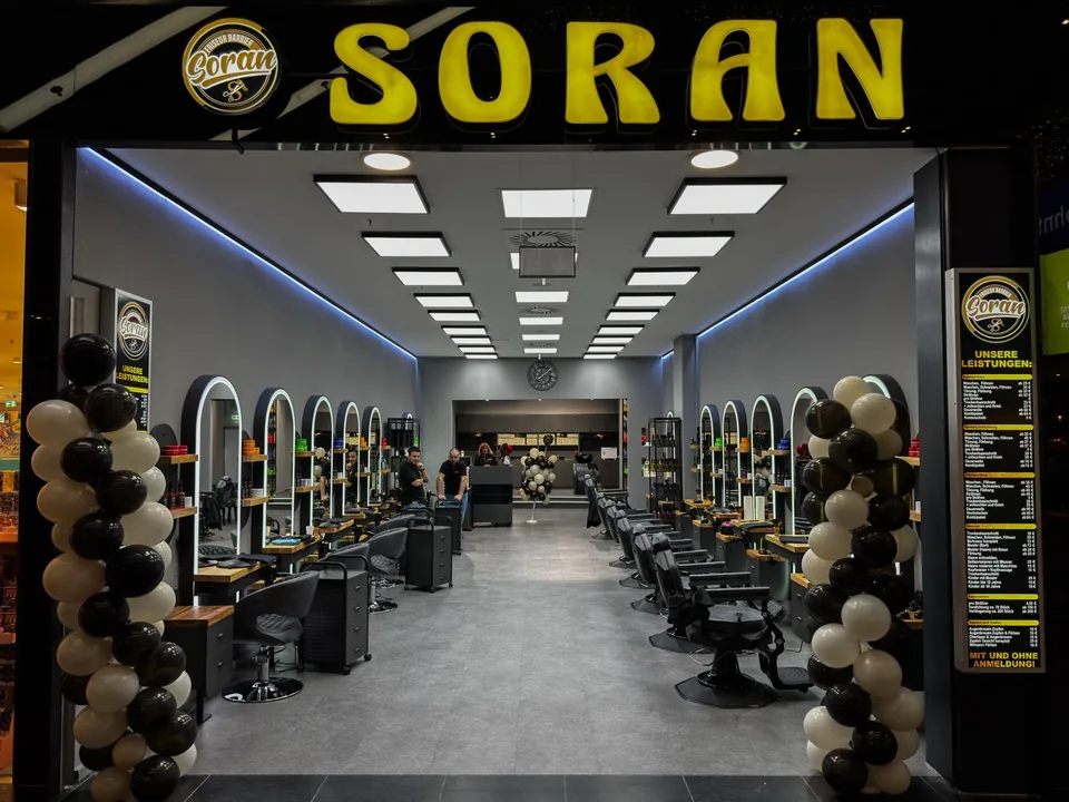 Frontansicht des Soran-Salons mit dem Logo über dem Eingang und auf beiden Leistungstafeln.
